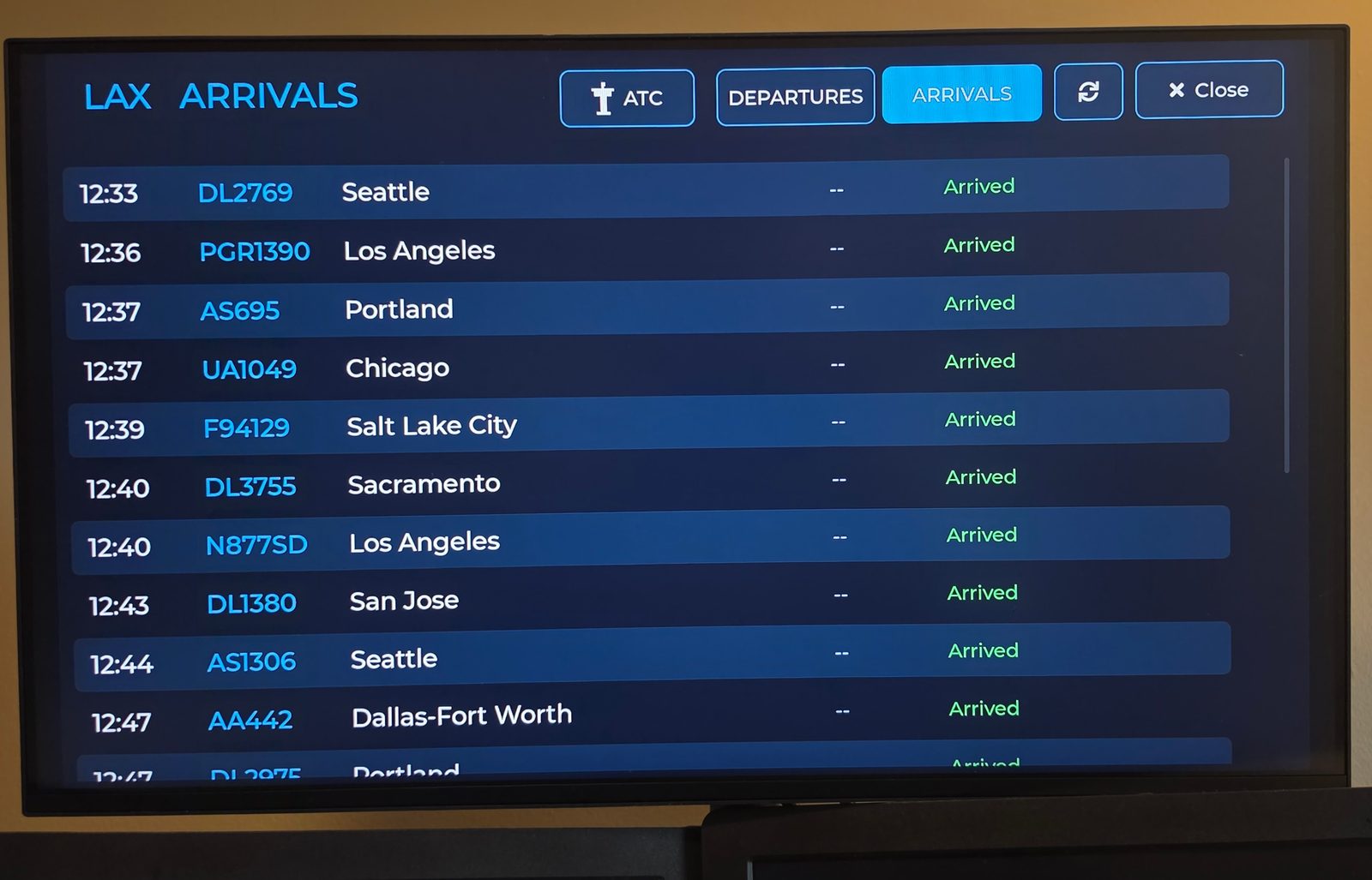 A TV showing the WingsAbove arrivals board for Los Angeles: arrival times, flight numbers, origins and status