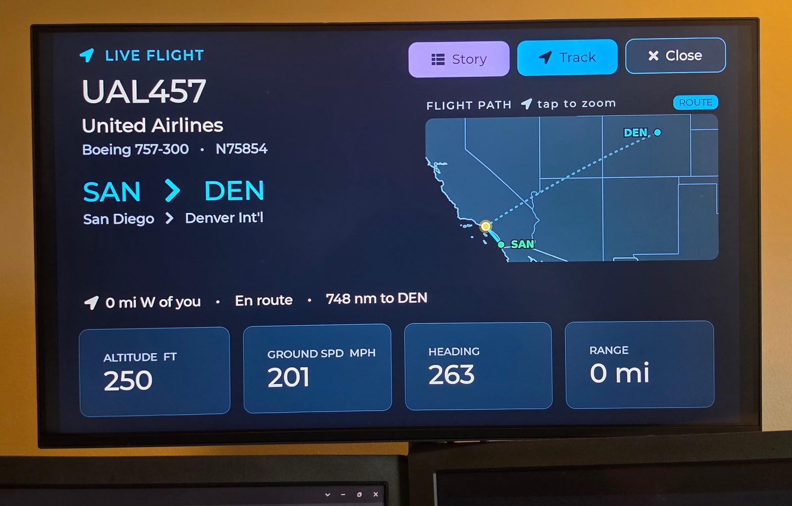 A living-room TV showing WingsAbove Cloud: a live United flight from San Diego to Denver with its route map, altitude, ground speed and heading